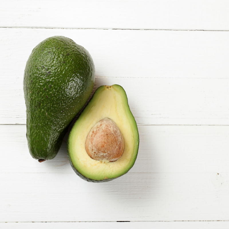 avocado cut open with seed on white board