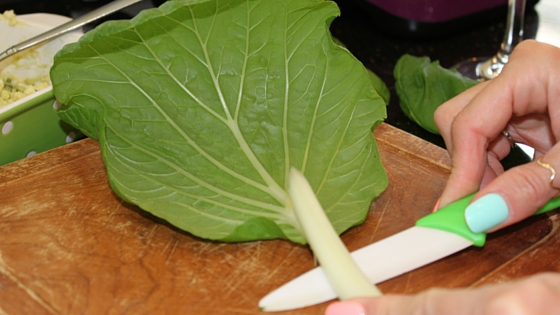 hand cutting the stem or vein in a leaf of bok choy