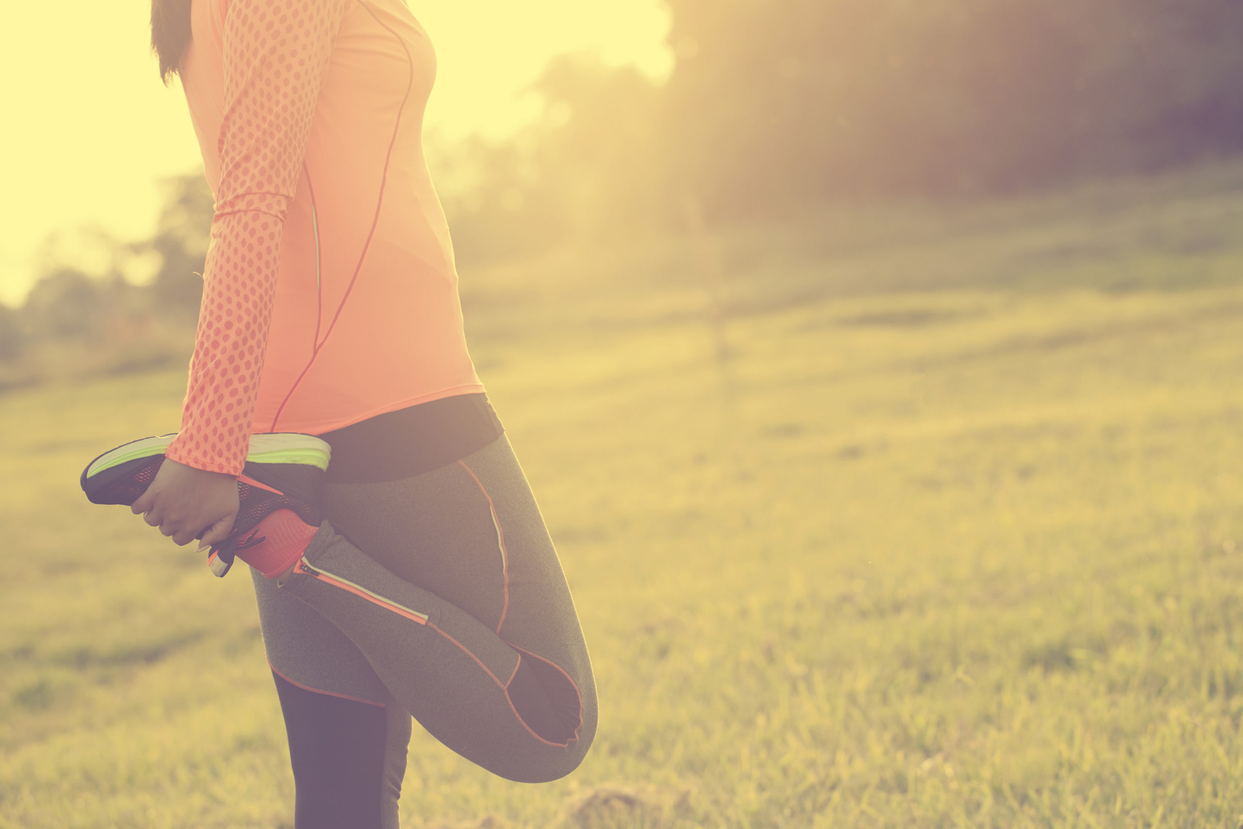 woman in meadow stretching before workout